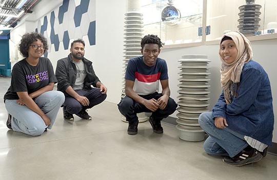 four young men 和 women posing in front of large ceramic insulators