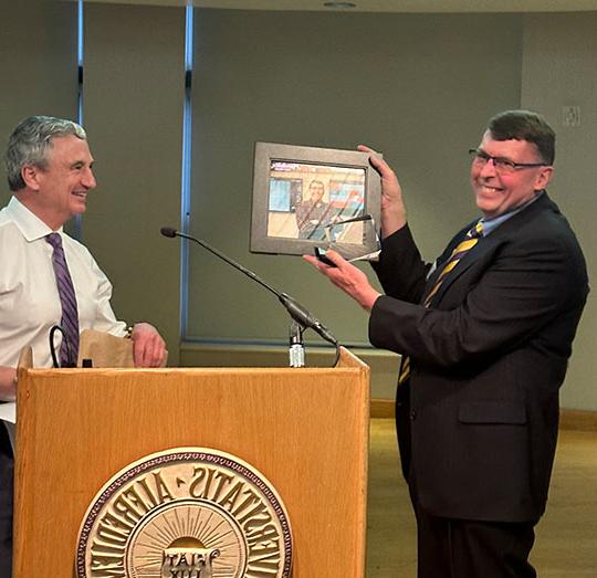 two men st和ing by a podium, one holding a plaque